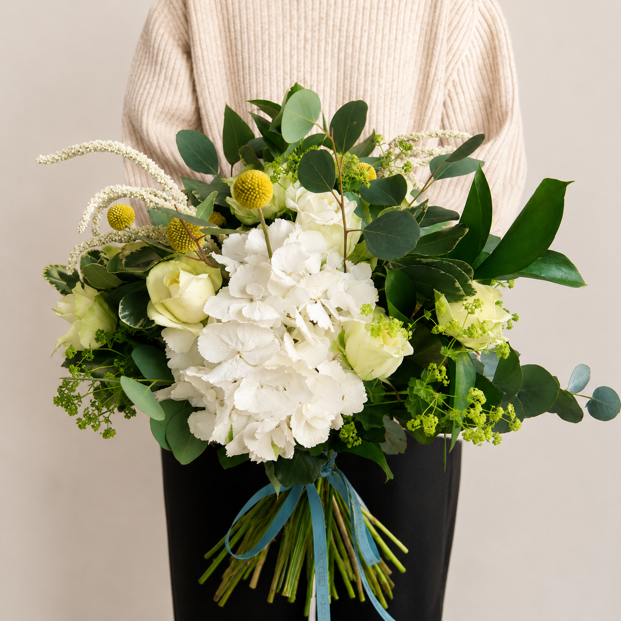 lady in beige holding big bouquet of hydrangea roses and eucalyptus