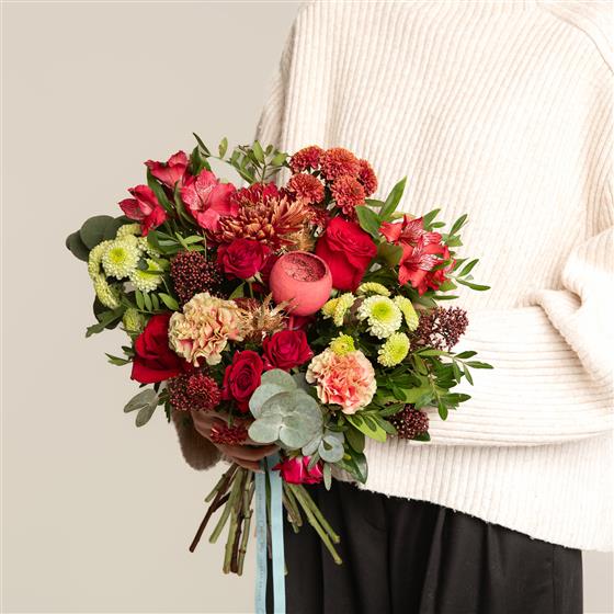 Bouquet of colorful flowers held by a person wearing a white sweater.