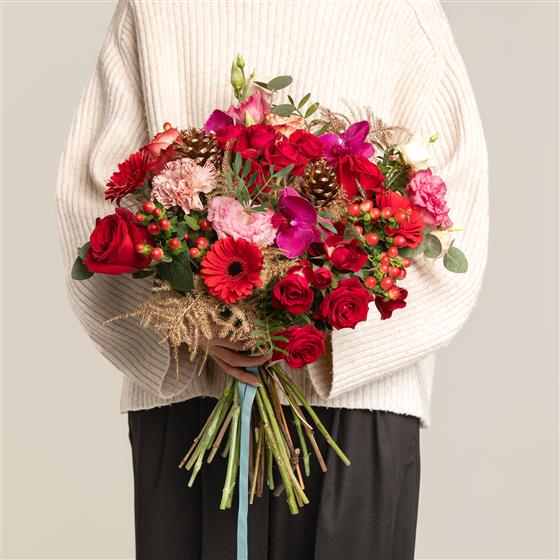 Person holding a vibrant bouquet of flowers against a neutral background