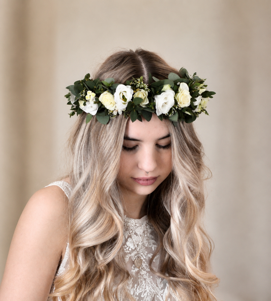 Woman wearing a floral headband with white and green flowers against a beige background