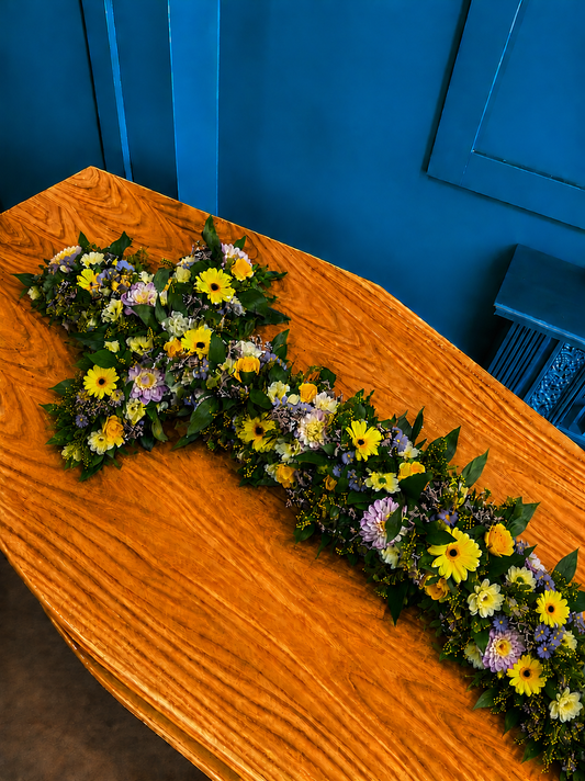 Floral arrangement on an orange coffin against a blue wall