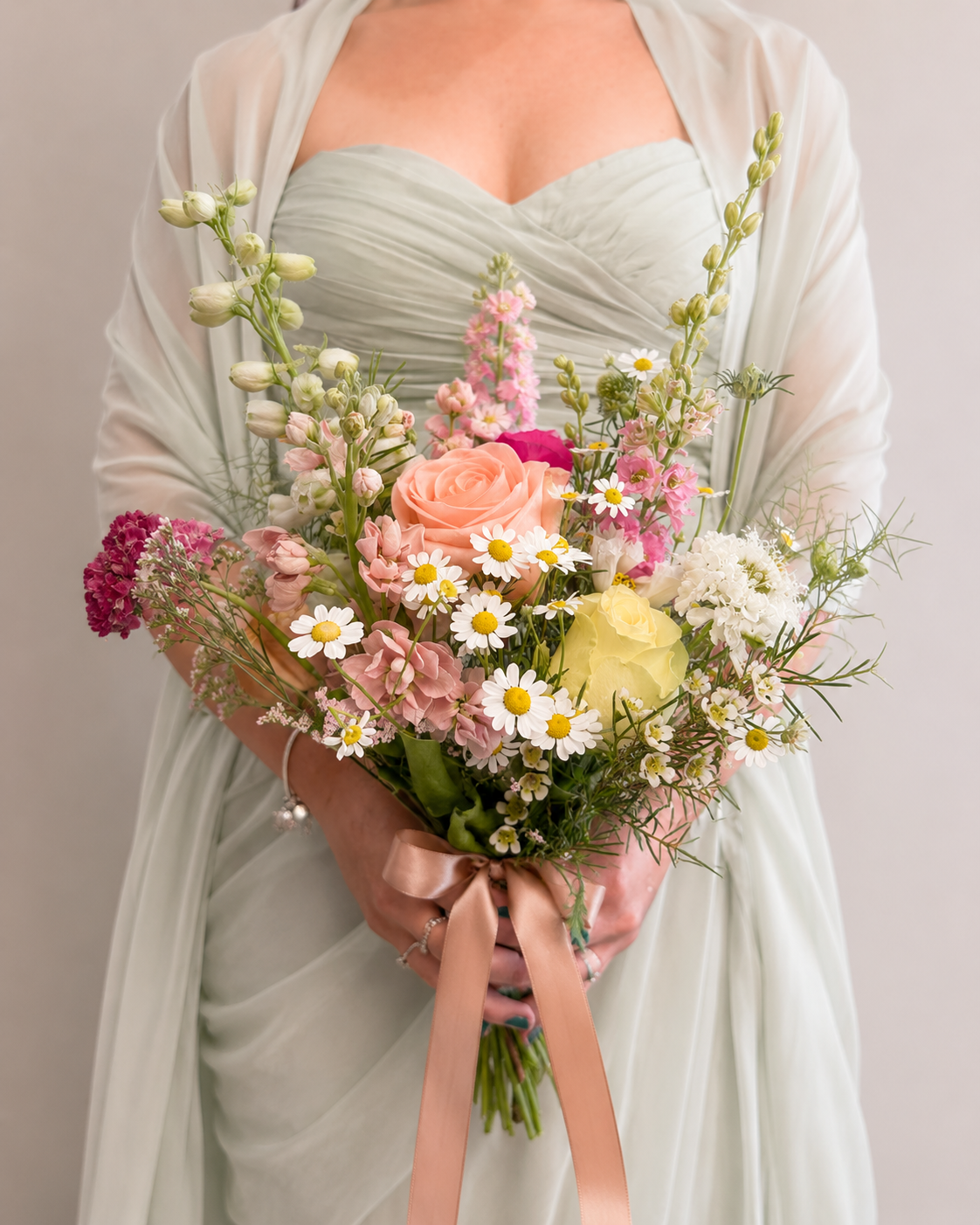 Person holding a bouquet of wedding flowers against a plain background