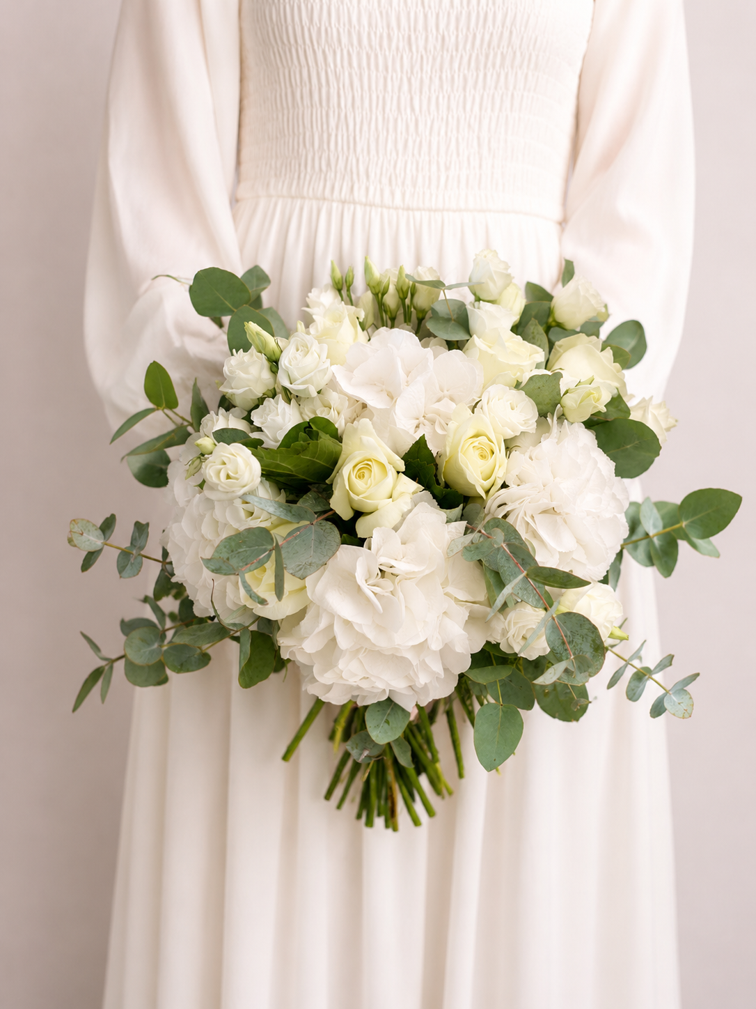 Bride holding Snowdrift Elegance Bridal Bouquet featuring white hydrangeas, ivory roses, spray roses and eucalyptus foliage.